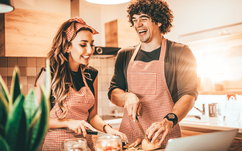 Young couple smiling and having fun while cooking a delicious recipe with biora's kombucha dressings and vinegars